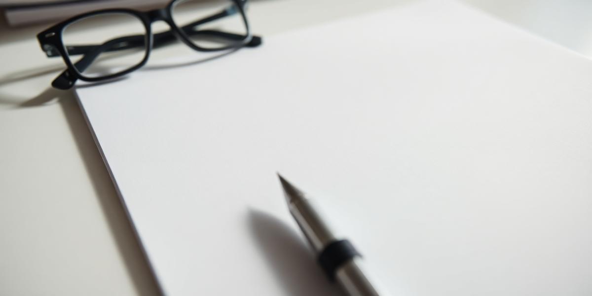Close-up of a blank printed lab report page beside black reading glasses and a pen on a bright desk